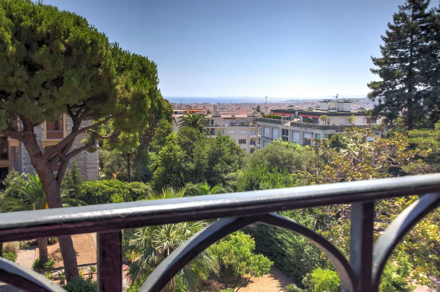 Vue dégagée sur les pins, la ville et la mer depuis le balcon d'un appartement à Cimiez